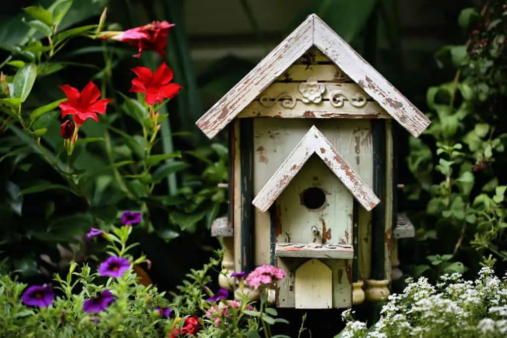 brown wooden birdhouse with red flowers
