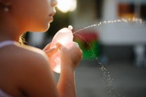 Little girl have fun with water balloon at home.
