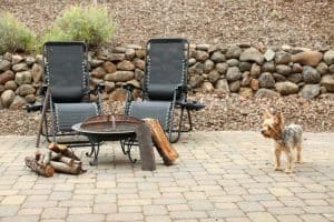 a couple of chairs and a fire pit on a brick patio