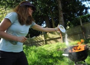 The last of the Sur, Charlotte offering the last bit of white food, silver compote, fire in a barbeque, backyard, grass, fence